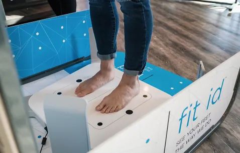 A Fleet Feet customer stands on a 3D scanner to take images of her feet